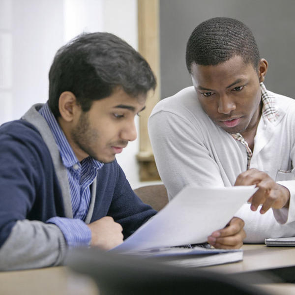 A young man helps a fellow student go over an assignment.