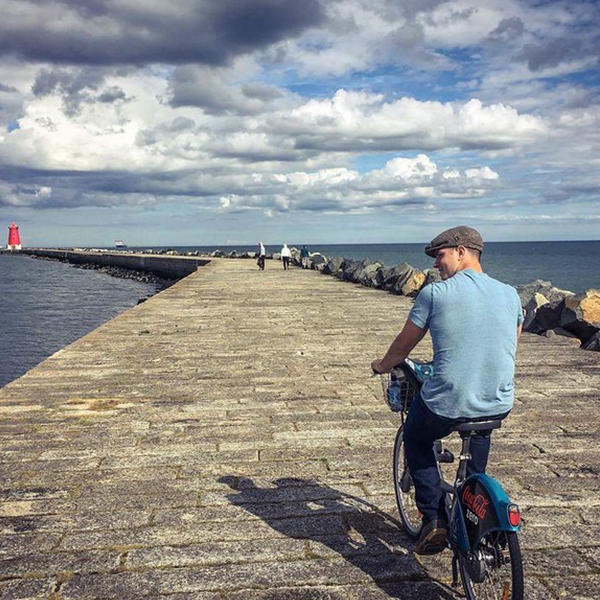 a young man bikes on a quay by the sea